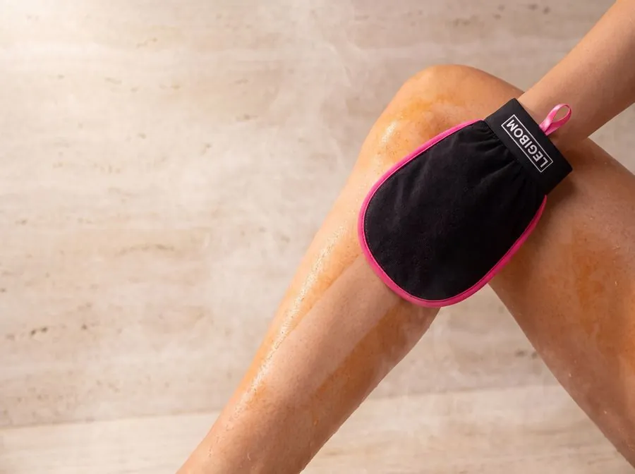 Removing patchy self tanner from a leg with a Legibom exfoliating mitt